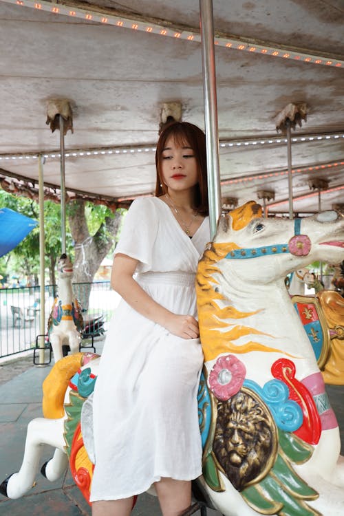 A woman in a white dress sitting on a carousel