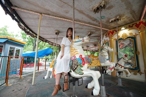 A woman is sitting on a carousel horse