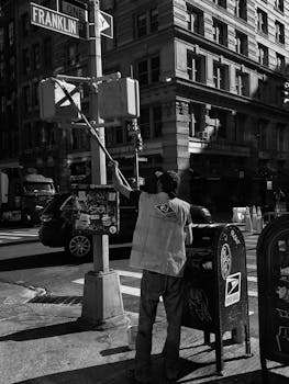 A street worker cleans in an urban setting on Franklin Street, city life captured in black and white.