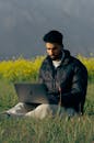 Man Working on Laptop Sitting in Grass Field