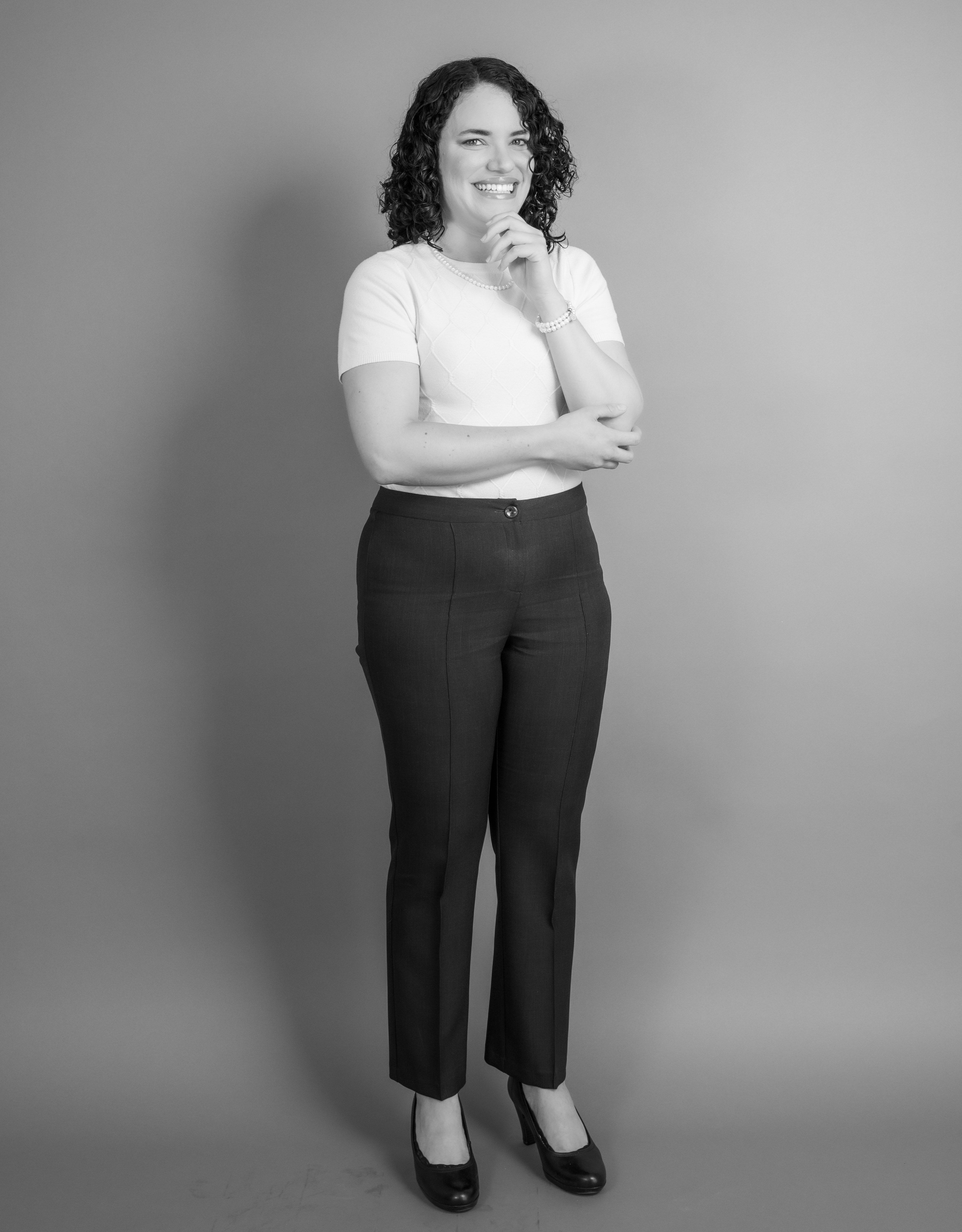 Black and white studio portrait of a smiling woman in stylish attire, Mexico City.
