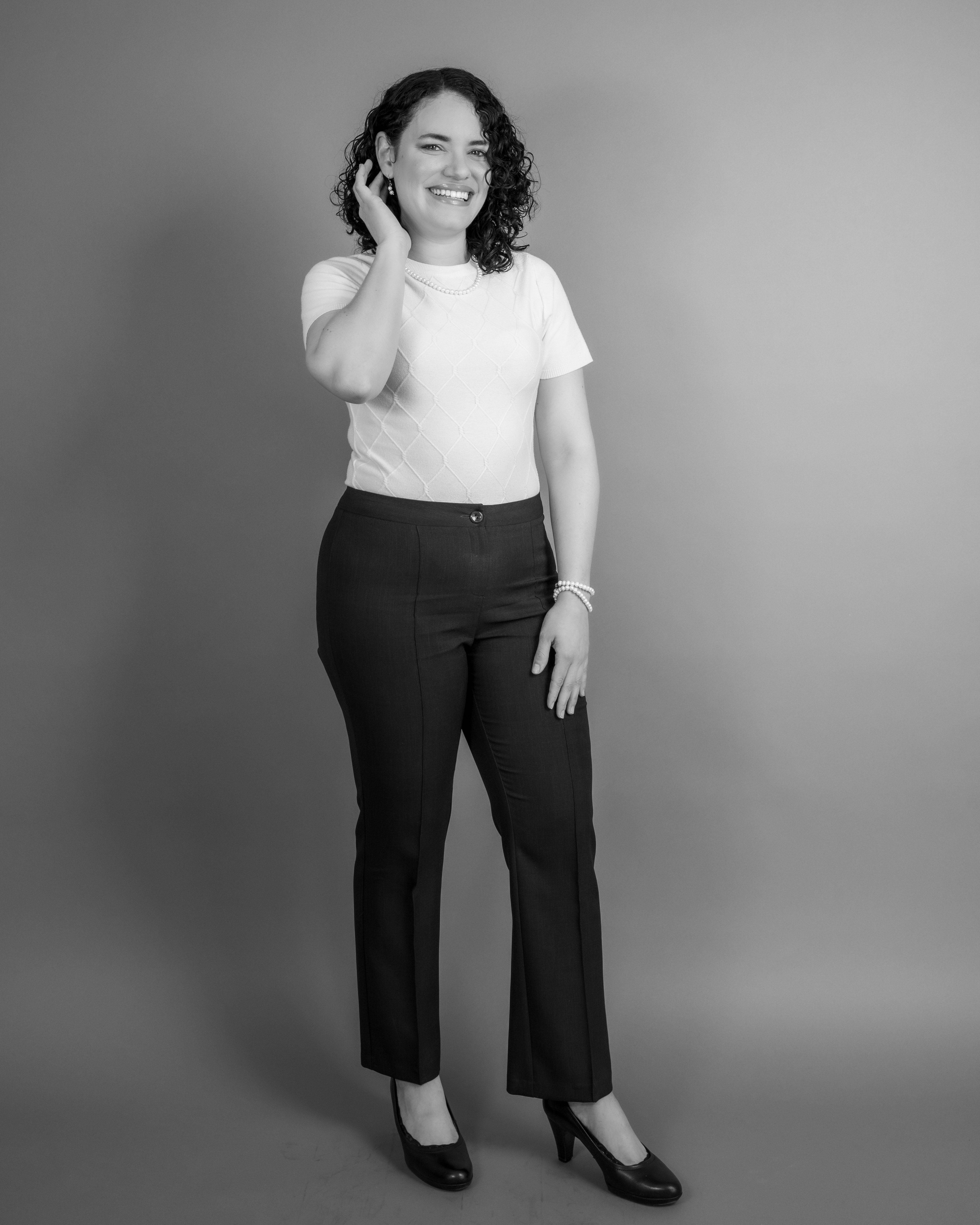 Stylish black and white portrait of a smiling woman standing in a studio.