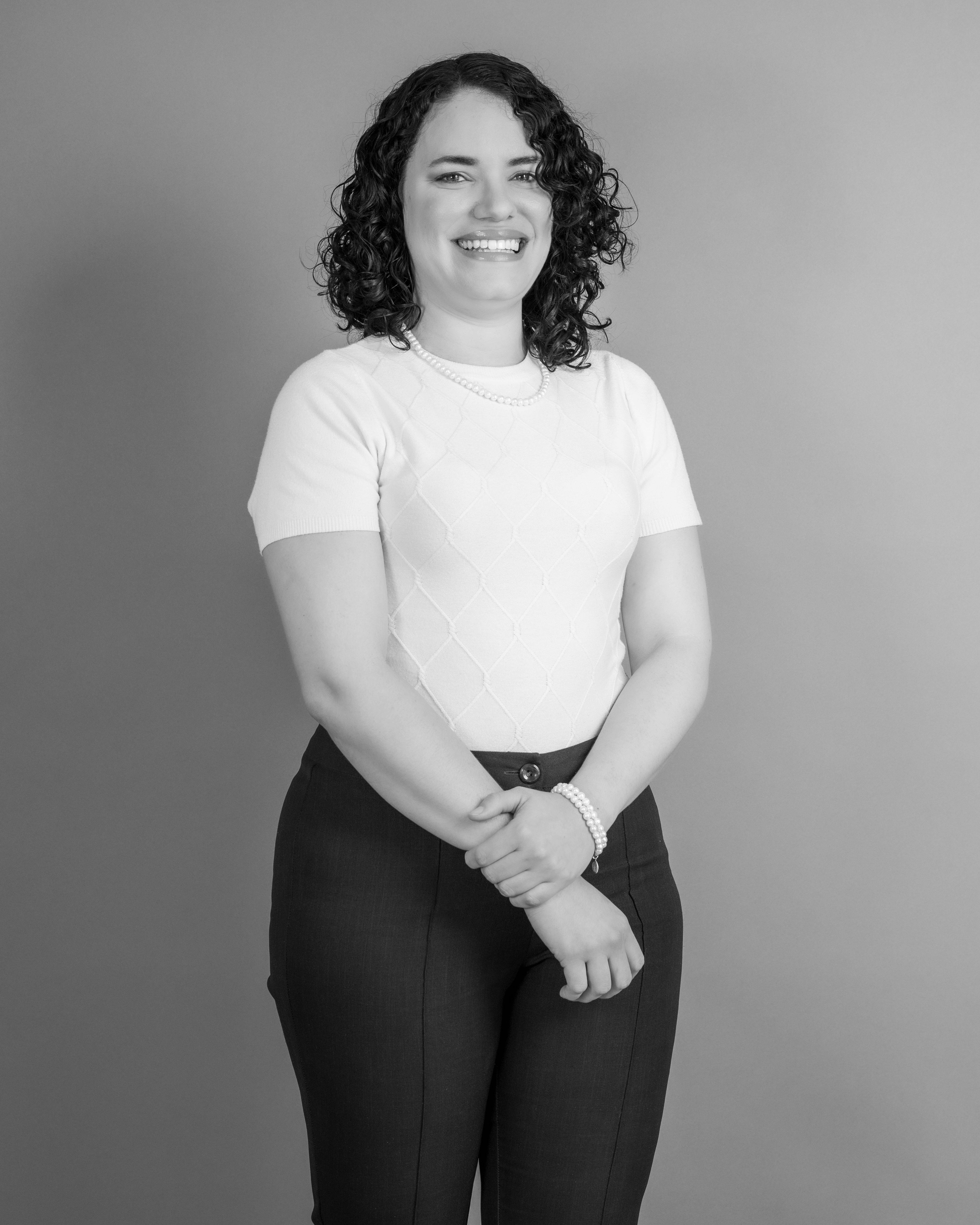 Stylish black and white portrait of a curly-haired woman smiling in a studio setting.