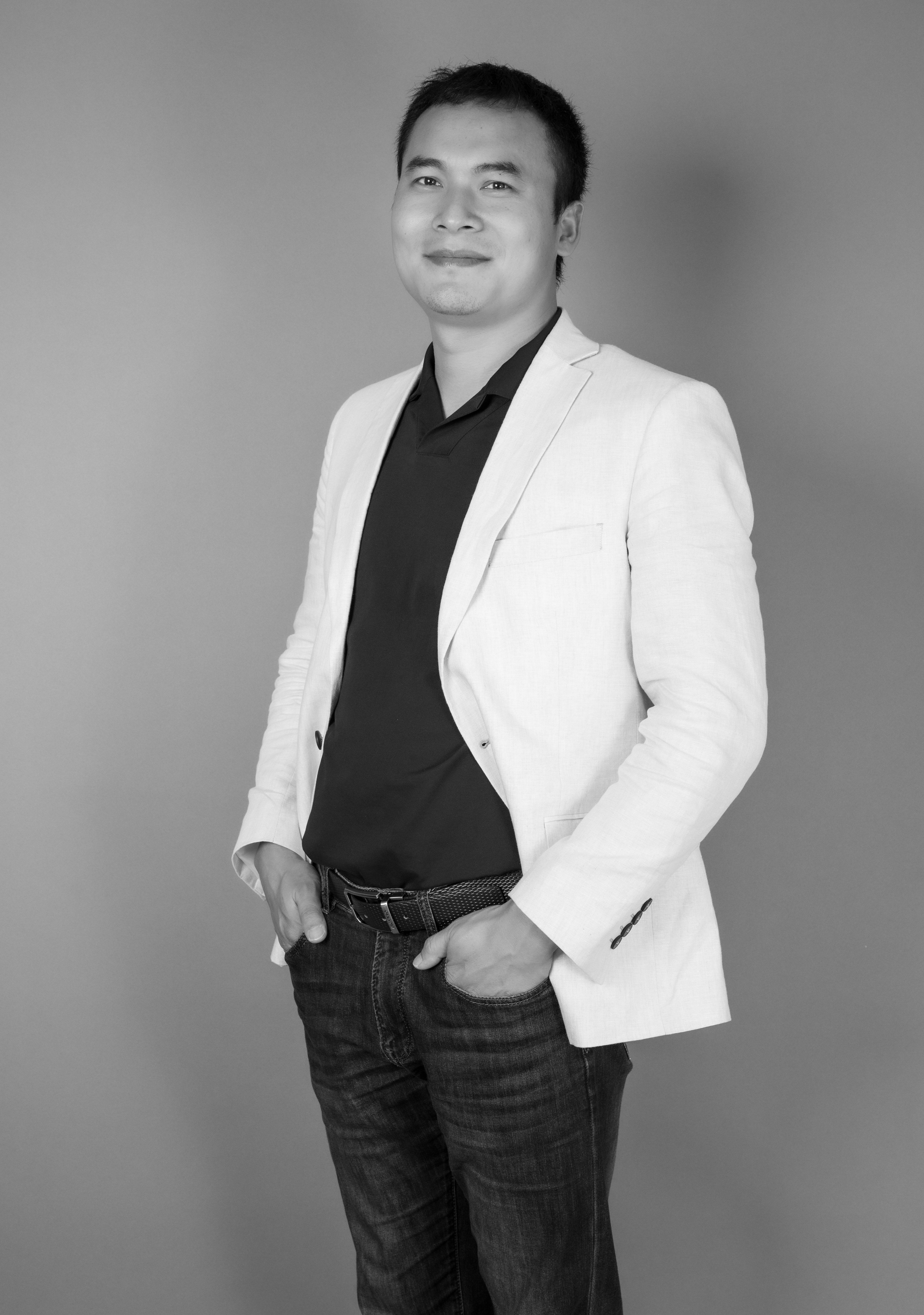 Black and white portrait of a confident young man in a studio setting, smiling.