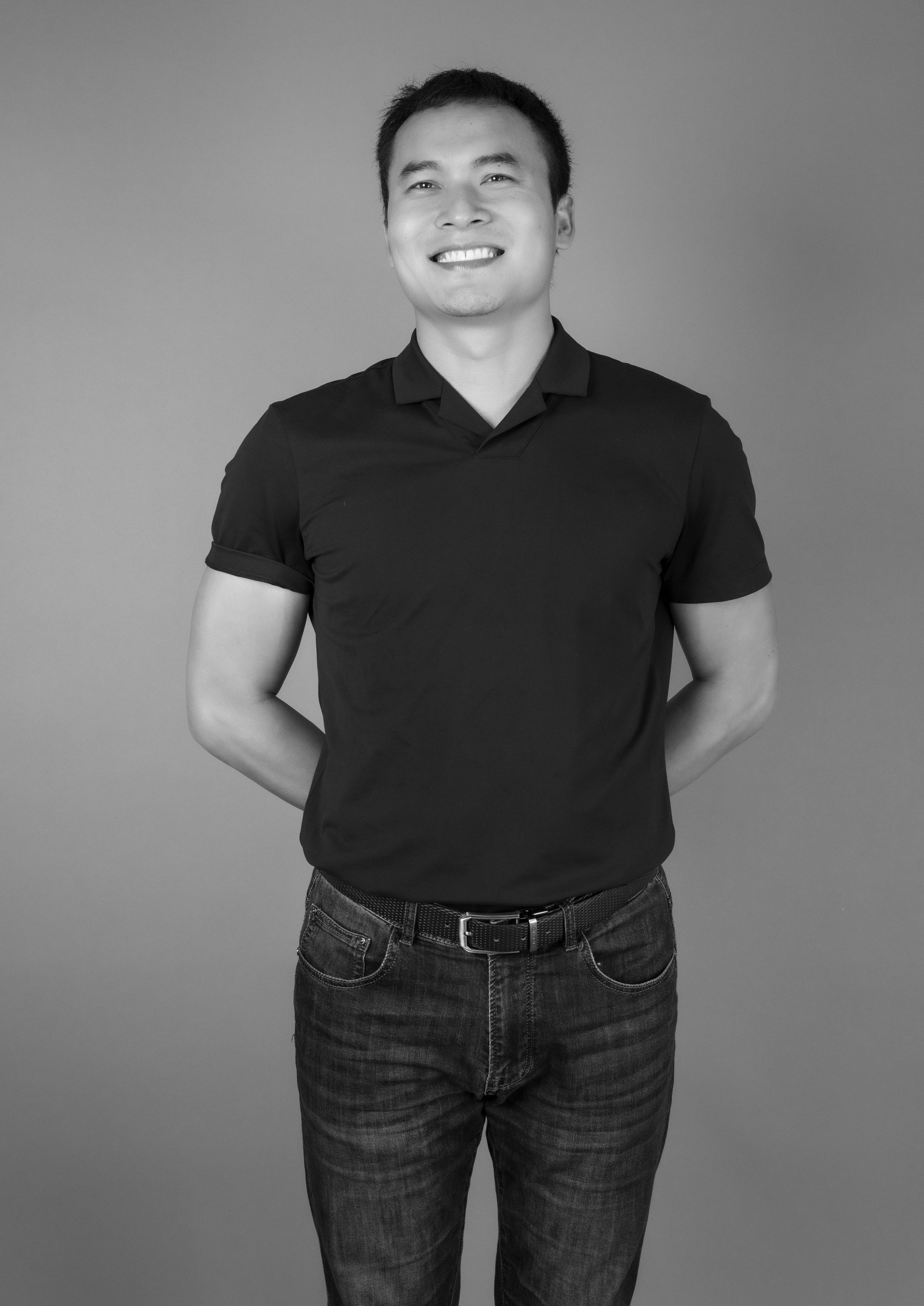 Studio portrait of a smiling Asian man in black t-shirt and jeans, Ciudad de México.