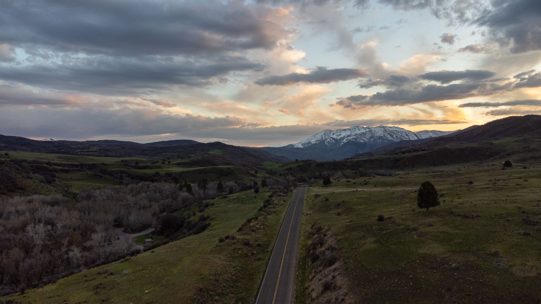 Scenic aerial view of Spanish Fork, Utah's rural landscape with mountains and a sunset sky.