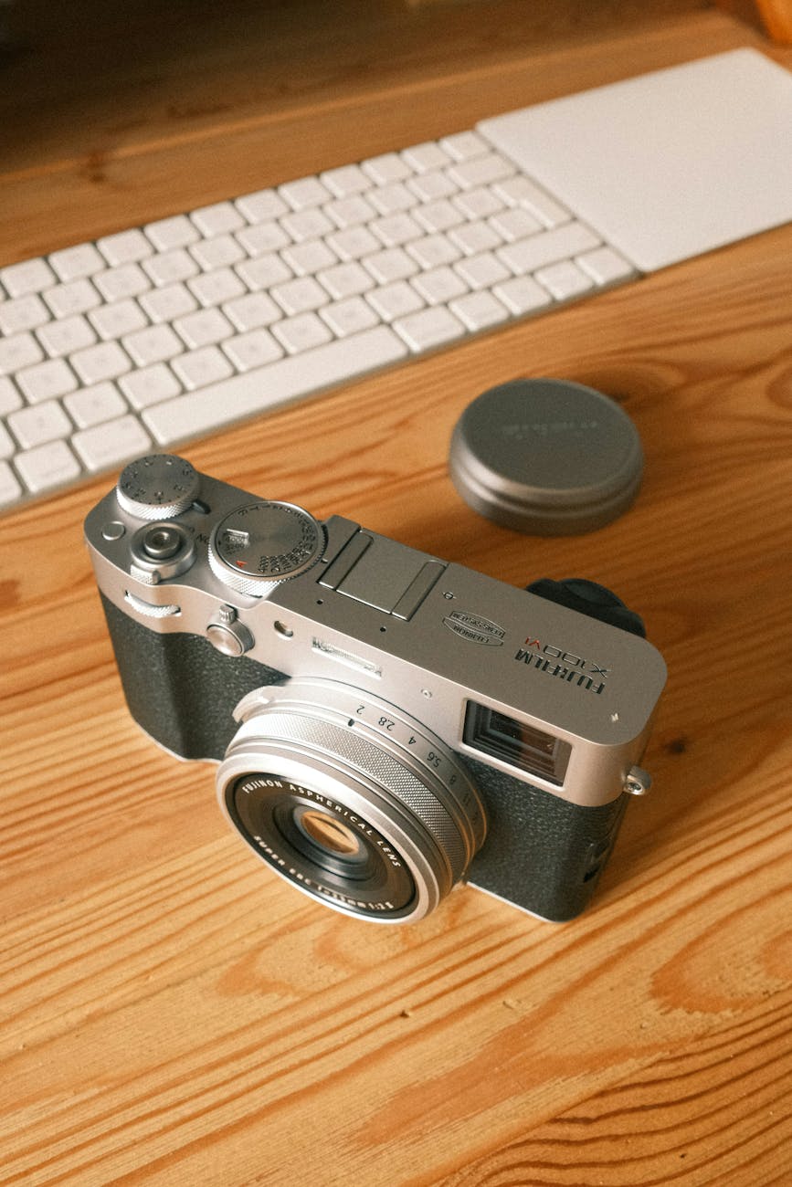 Classic analog camera with keyboard on a wooden desk, evoking nostalgia and creativity.