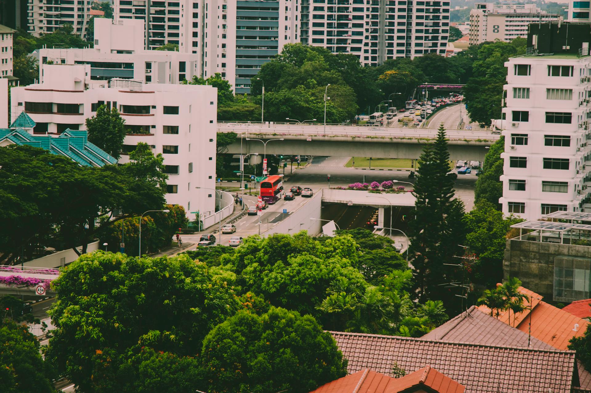 A vibrant aerial cityscape of Singapore featuring modern architecture, lush greenery, and busy roads.