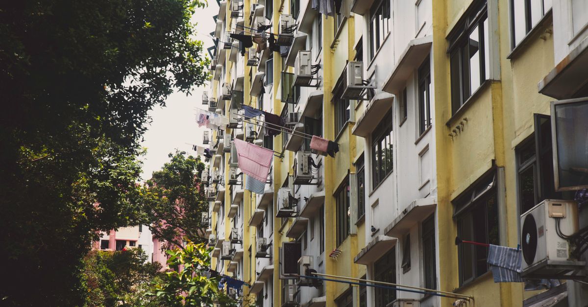 Colorful apartment building facade in urban Singapore with laundry visible, capturing city life.