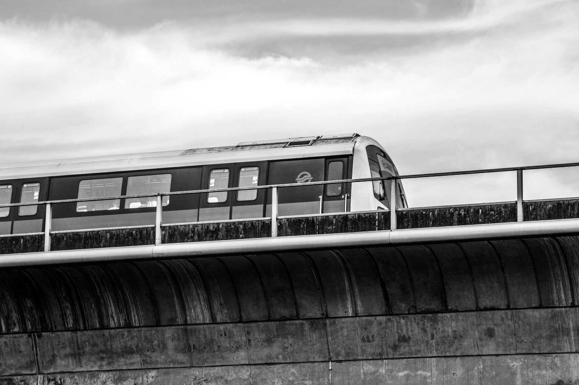 Black and white photo of a train on an elevated track in Singapore's public transport system.