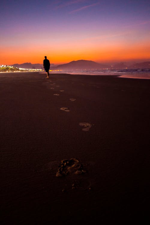 gratis Silhouetfotografie Van Een Persoon Die Naast Het Strand Loopt Stockfoto
