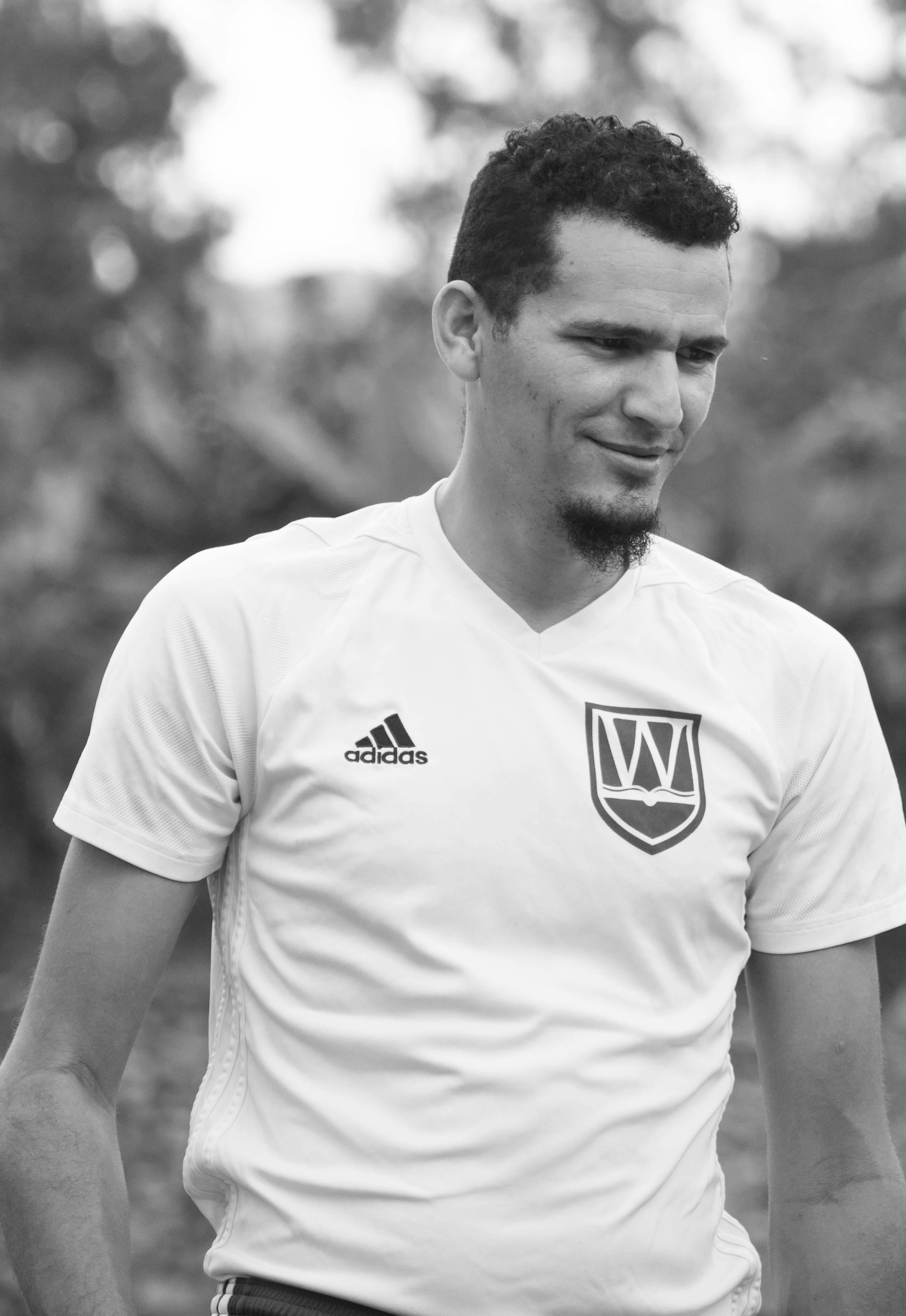 Black and white portrait of a male soccer player in Edmonton, showcasing a relaxed moment.