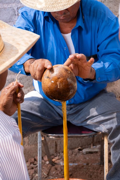 Free A man in a straw hat is pouring a liquid into a cup Stock Photo