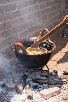 Cooking a stew outdoors in a large pan over an open fire, with wooden stirring.