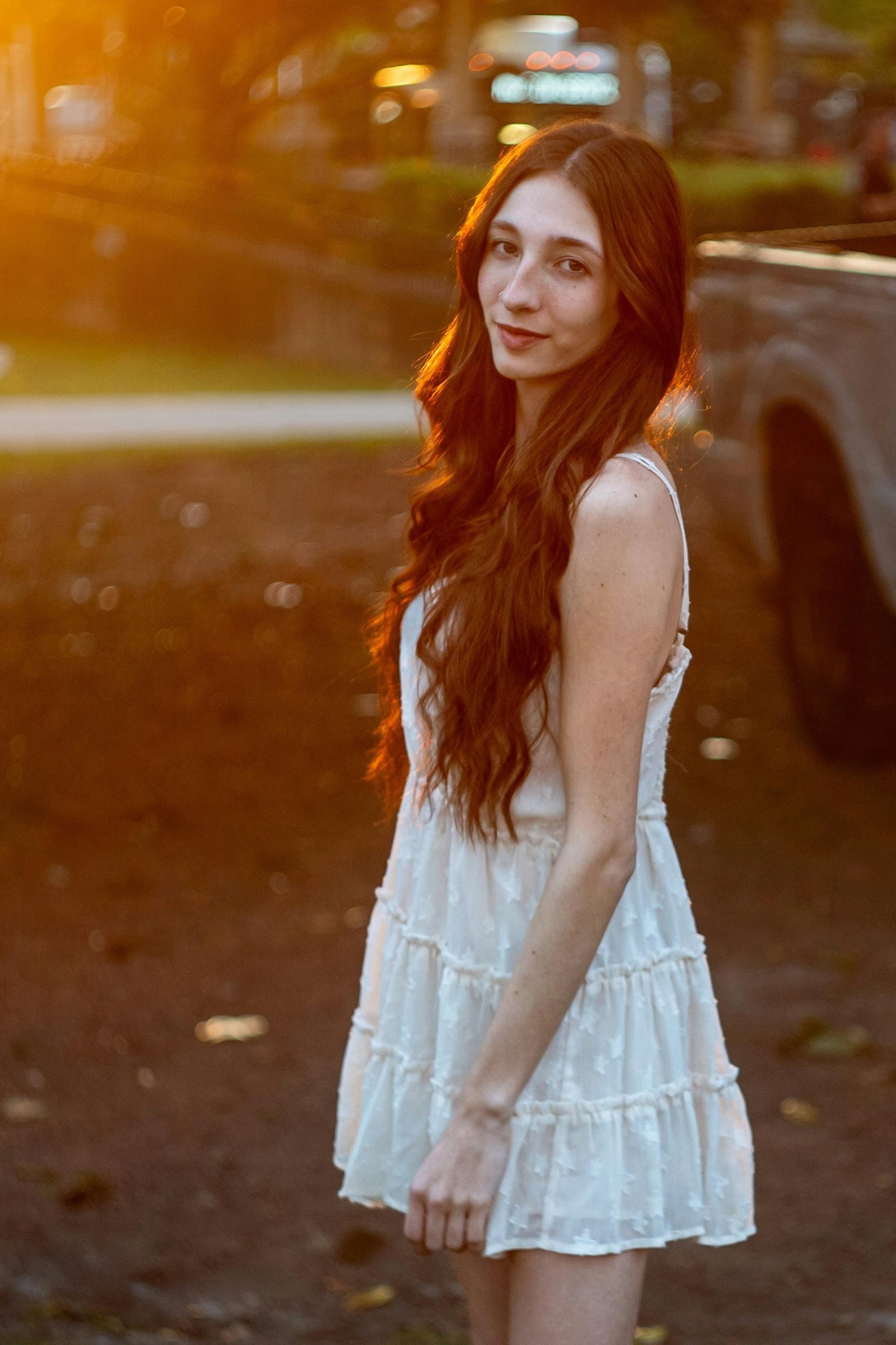 young woman in white dress posing outside