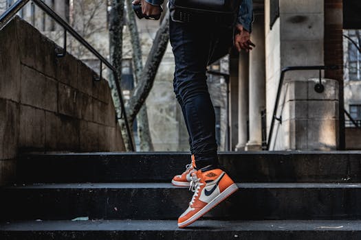 在城市环境中，一个人穿着时尚的橙色和白色运动鞋爬户外楼梯