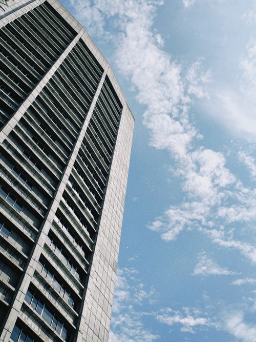Free Tall skyscraper against a clear blue sky with white clouds. A modern architectural marvel. Stock Photo