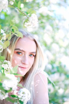 阳光明媚的户外，一位年轻的金发女子微笑着，周围开满白花