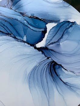 Photo by Marten Kunitsa Artistic abstract image of flowing blue ink on a white surface.