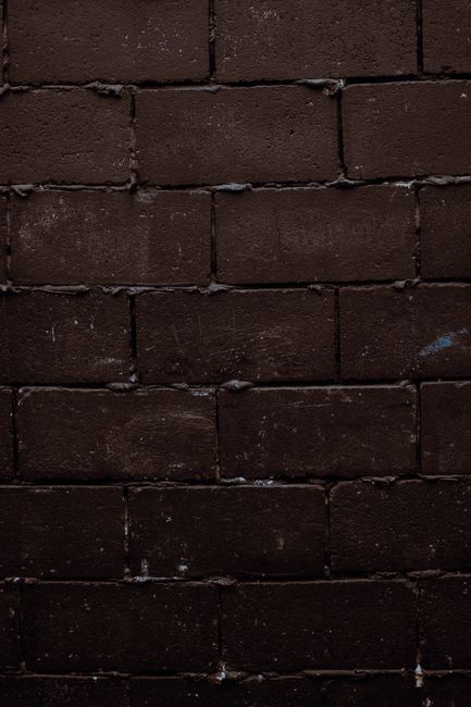 Close-up texture of a dark, rough brick wall, perfect for backgrounds.