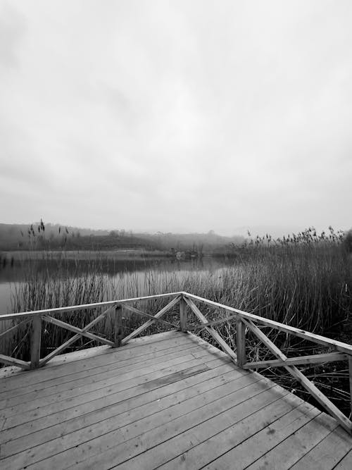 A black and white photo of a wooden walkway over a lake