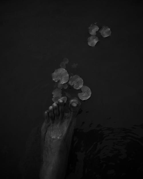 A black and white photo of a person's feet in water