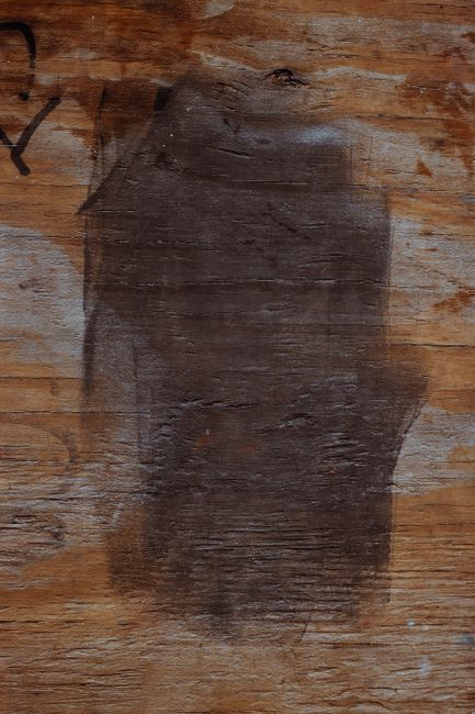 Detailed view of a textured wooden surface with a dark stain, highlighting natural patterns and weathering.