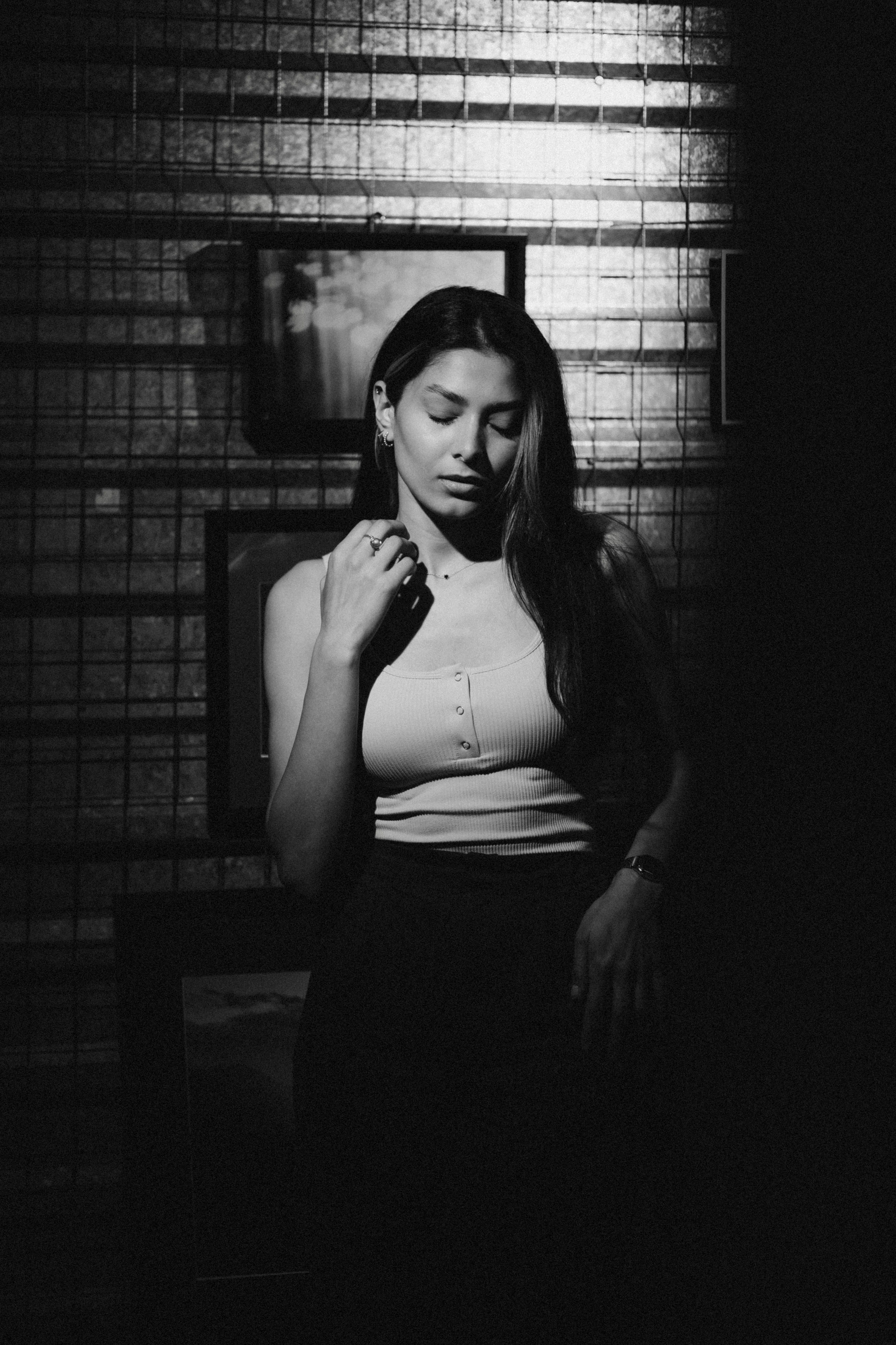 Black and white photo of a woman posing against a textured wall.