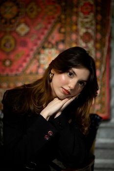 A graceful portrait of a woman with long brown hair posing indoors against a decorative background.