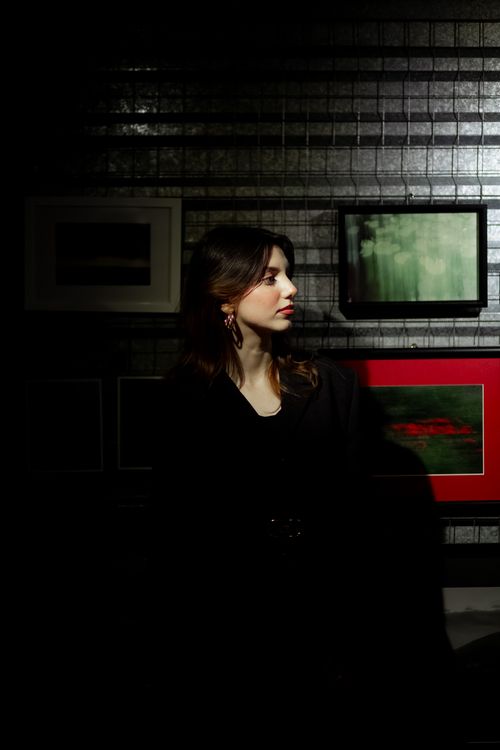 Free Dramatic portrait of a woman with brown hair in an art gallery with dim lighting. Stock Photo