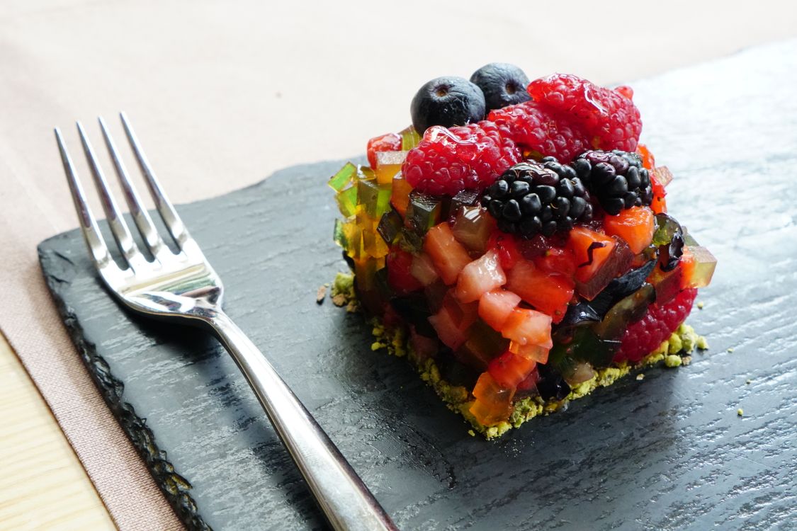 Free A vibrant mixed berry dessert featuring raspberries, blackberries, and blueberries served elegantly on a slate plate with a fork. Stock Photo
