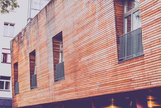 Contemporary wooden facade of a residential building with windows and railings, showcasing urban architecture.
