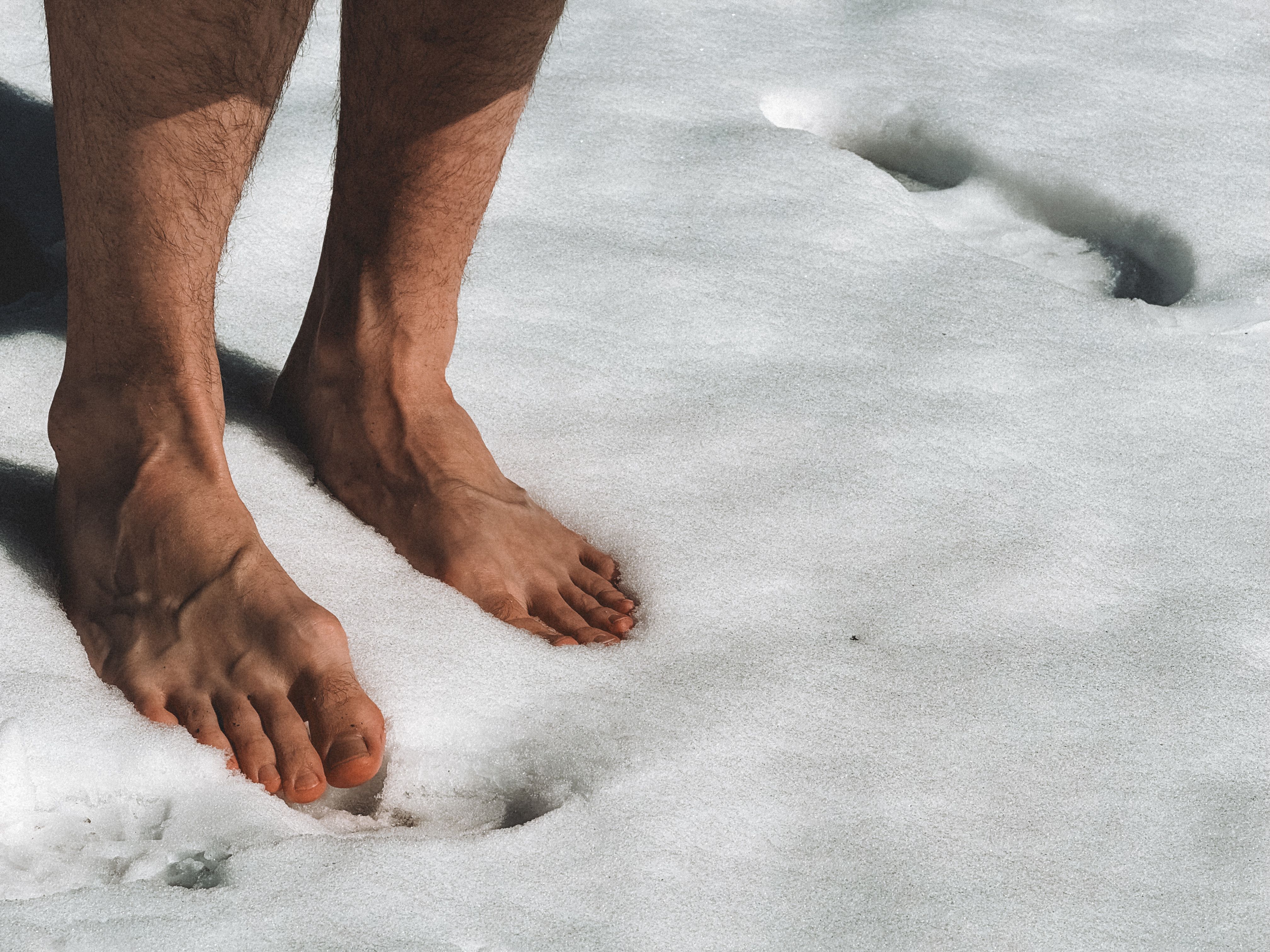 Close-up of a barefoot man standing on snow in Fitz Roy, Argentina during winter.