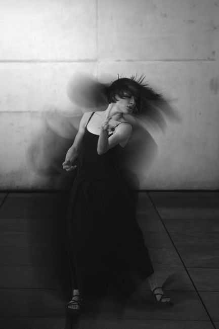 Dynamic black and white photo of a woman dancing with motion blur in Berlin.