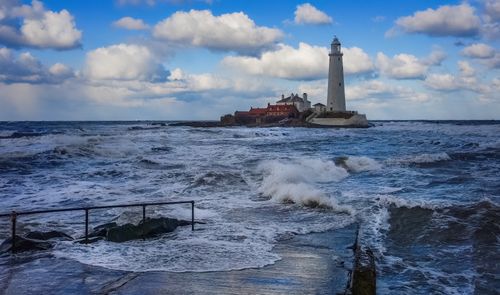 Free Dramatic view of St Mary's Lighthouse amidst turbulent waves on a bright day. Stock Photo