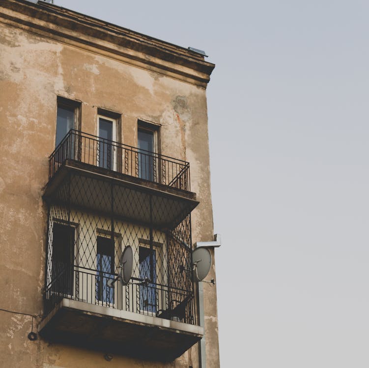 бесплатная Серая параболическая антенна висит на коричневом здании Стоковое фото