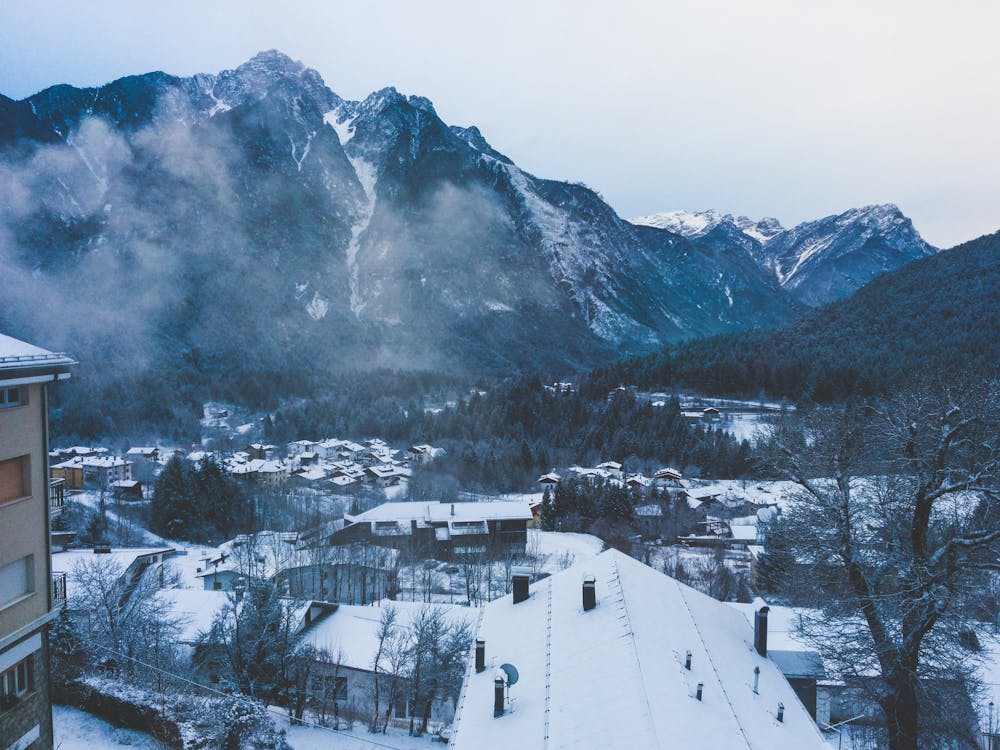 бесплатная Заснеженный дом возле заснеженной горы под ясным небом Стоковое фото