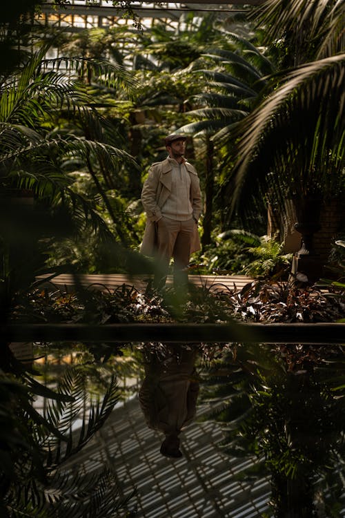 A man standing in front of a pond in a greenhouse