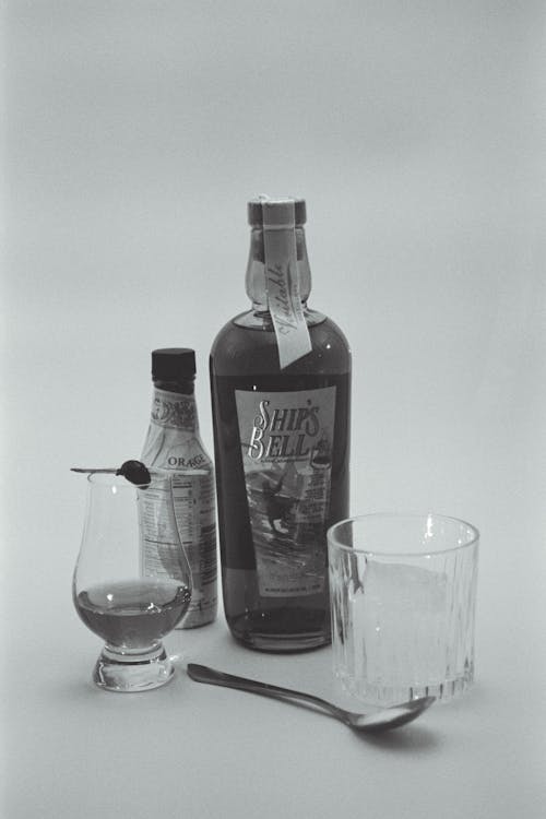 A black and white photograph of a bottle of whiskey and a spoon