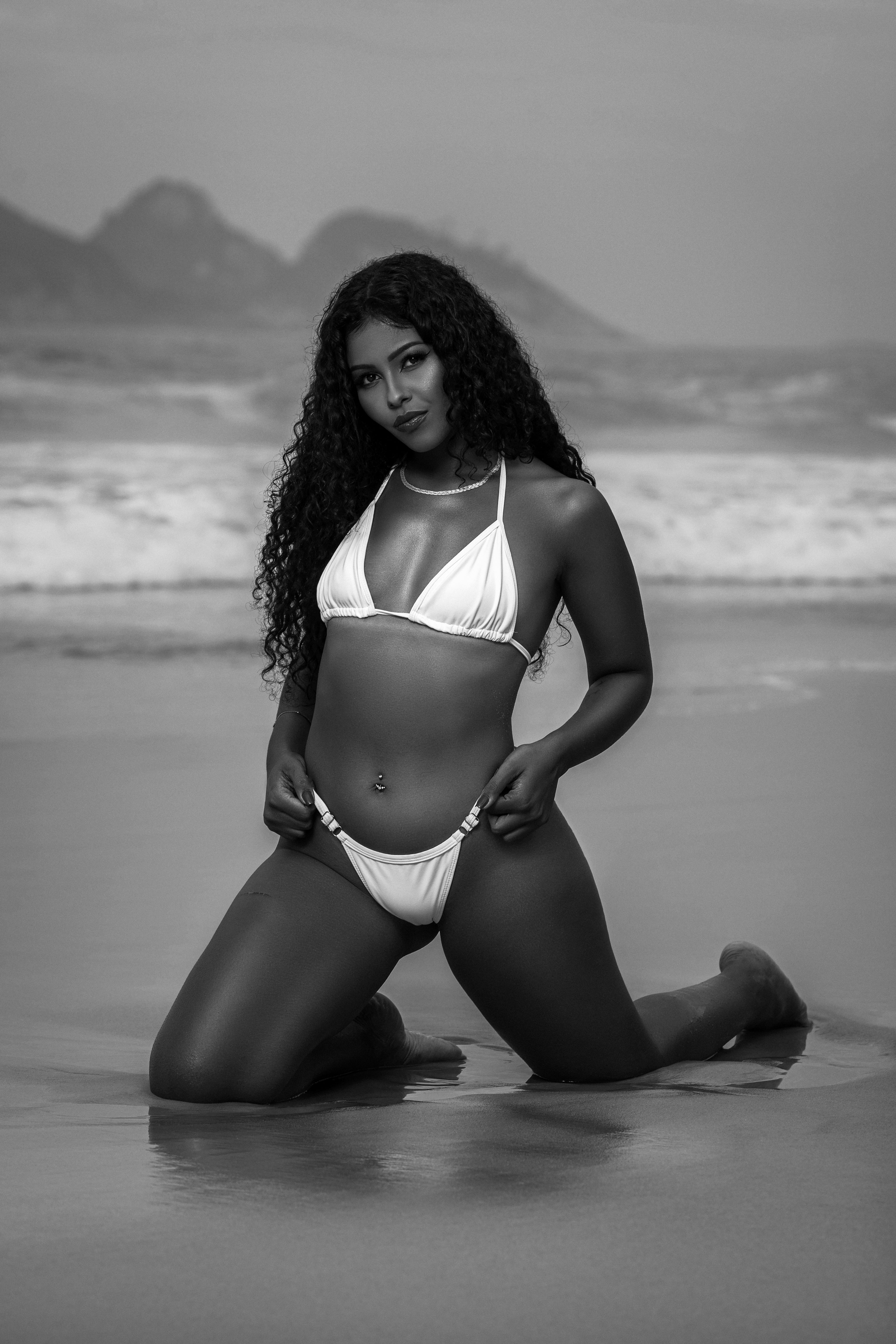 时尚的黑白照片，一位穿着比基尼的女子在海滩上摆姿势