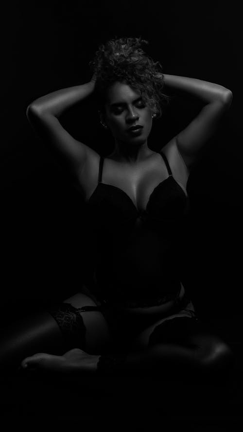 A woman in black lingerie posing in a dark room