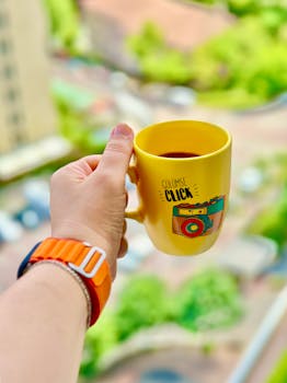 Colorful yellow mug with coffee in hand overlooking İstanbul view, vibrant and fresh.