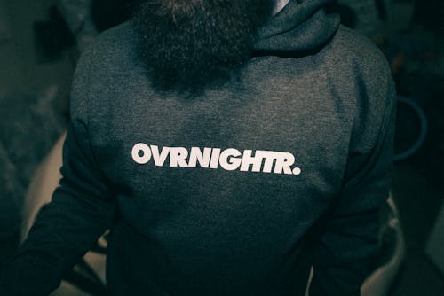 A man with a beard wearing a hoodie that says overnight