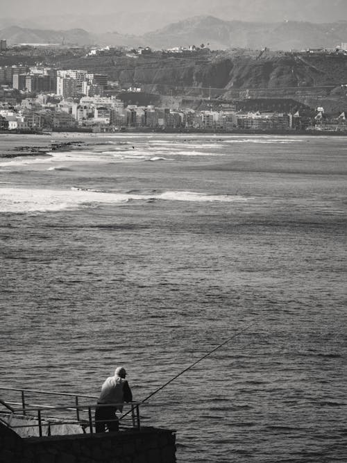 A man fishing on the beach near the ocean