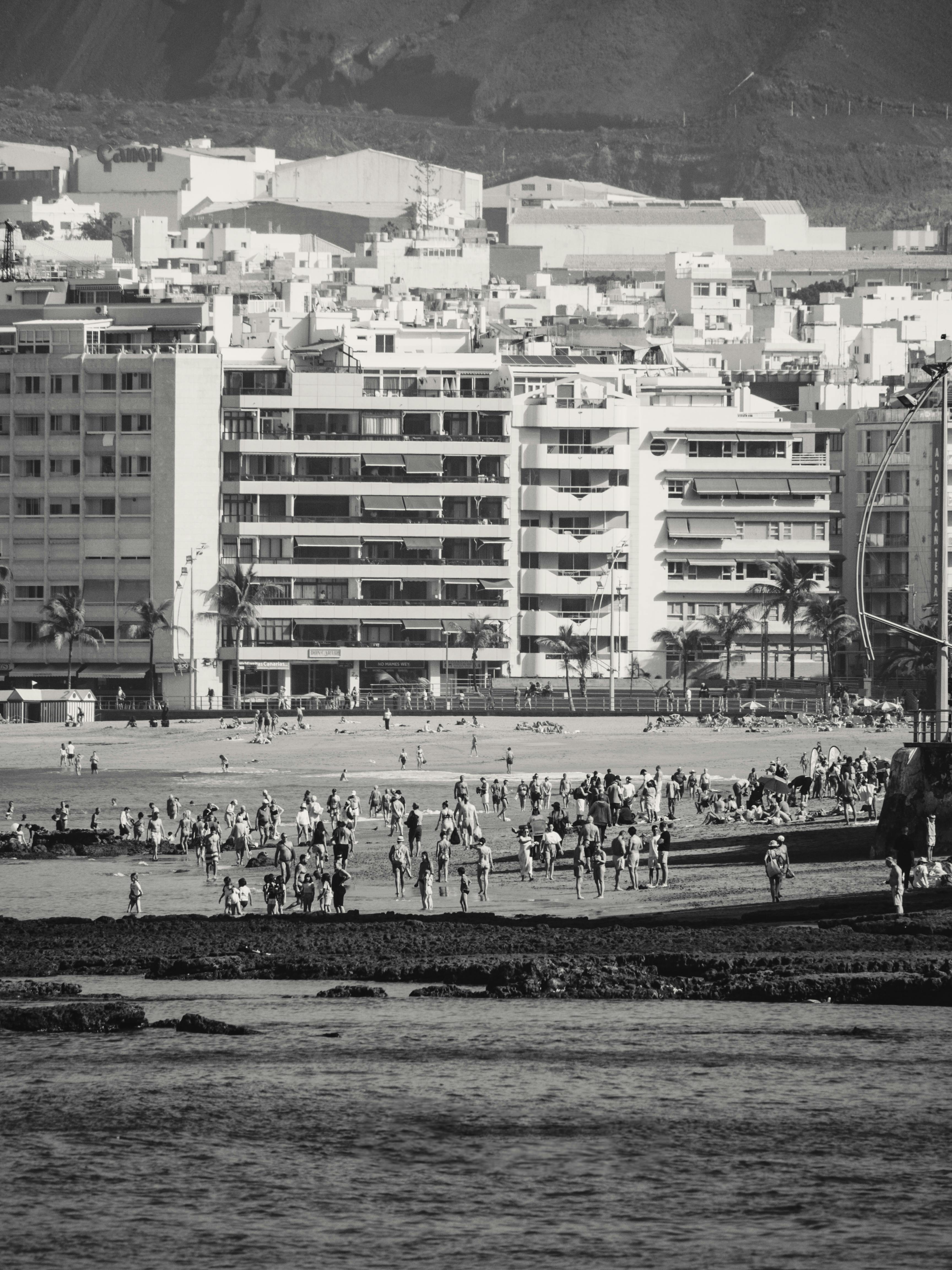 Black and white photo of a busy beachfront city with people enjoying the shore.