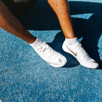 Close-up of an athlete's legs wearing Nike soccer cleats on a vibrant blue surface.
