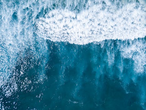 Captivating aerial shot of ocean waves crashing on a blue sea from above, showcasing nature's beauty.