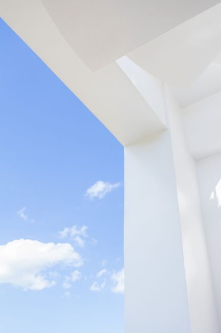 Sleek white structure with blue sky and clouds, showing minimalist architectural design elements.