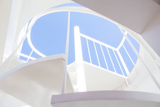 现代化的白色螺旋楼梯在清澈的蓝天下向上延伸，展现出建筑的优雅