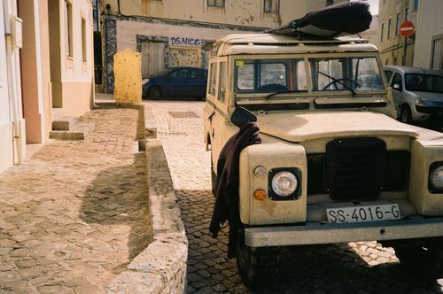 Free A classic Land Rover parked on a sunny cobblestone street in Ericeira, Portugal. Stock Photo